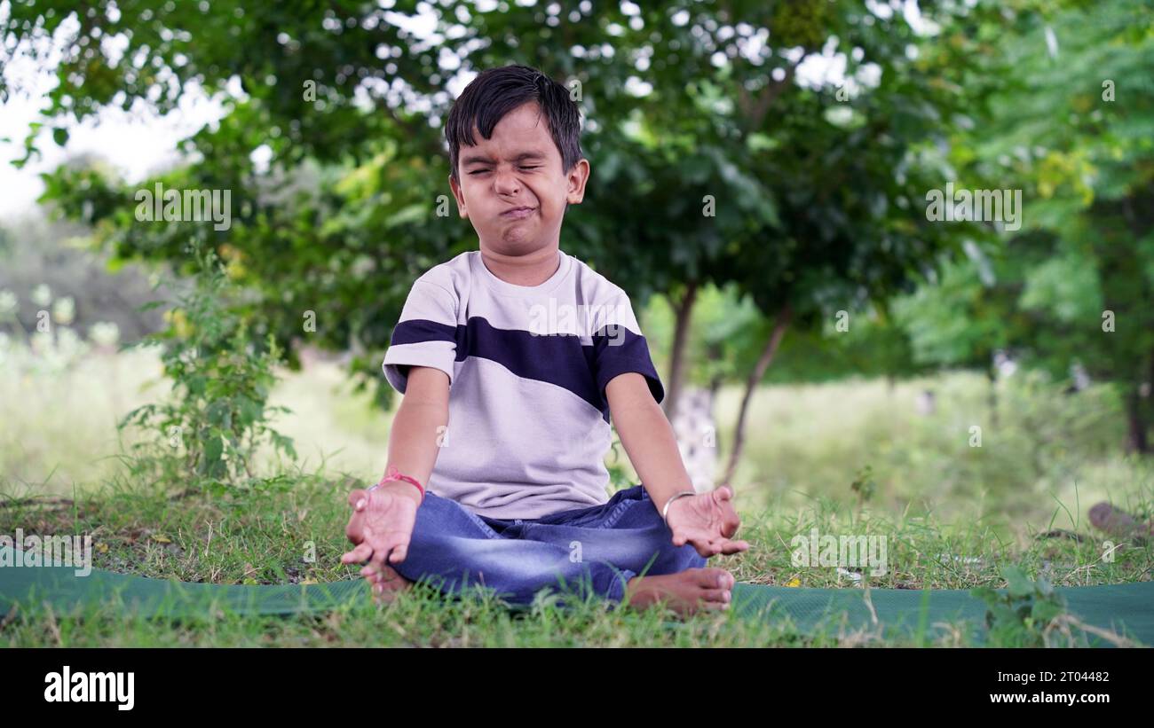Portrait of gorgeous kid practicing yoga outdoor. Beautiful child practice yoga asana or doing gymnastic exercises. Little kids meditating in lotus po Stock Photo