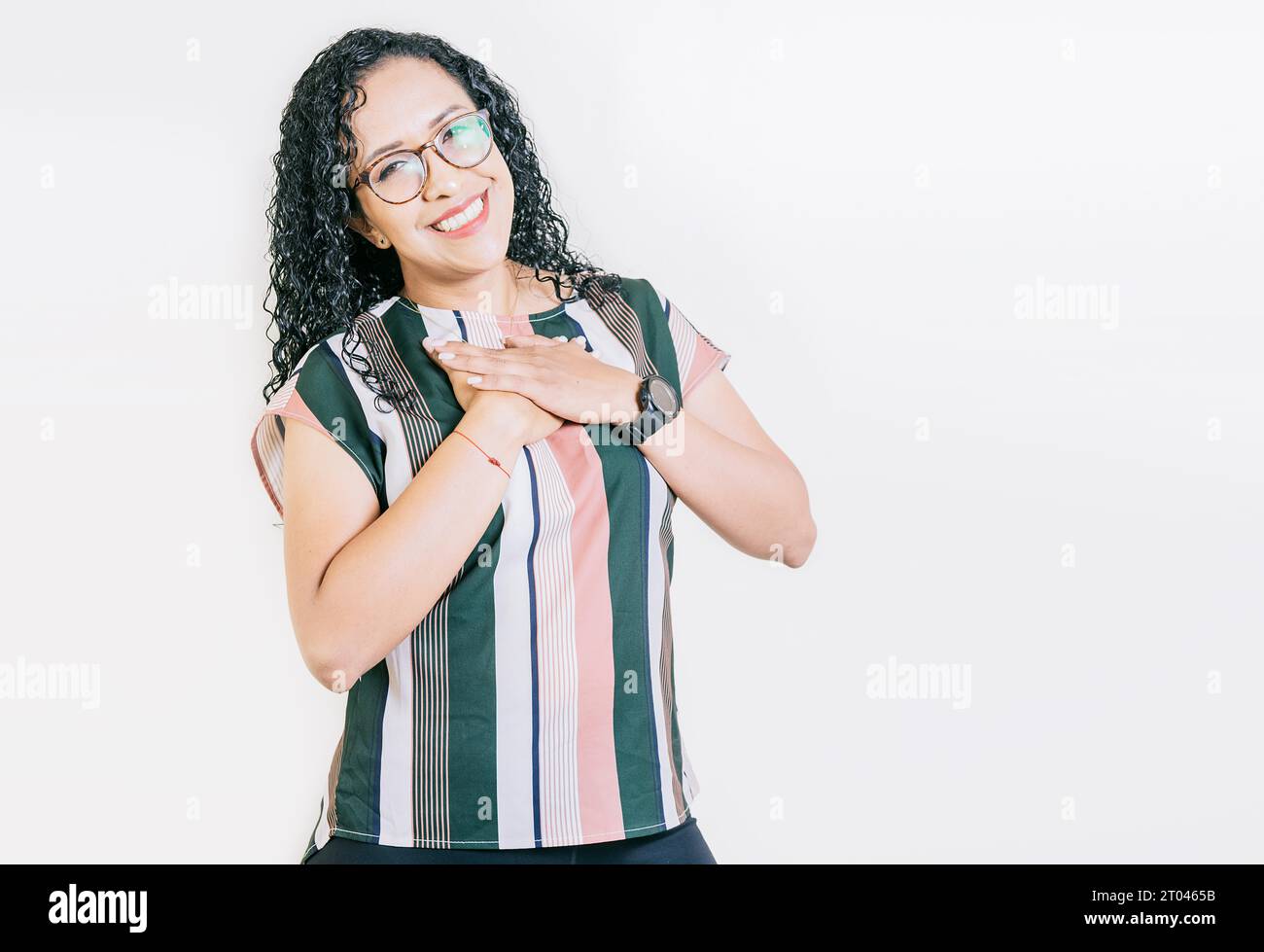 Grateful young woman smiling with hands on chest isolated. Positive smiling girl with hands on chest. Grateful people with hands on chest Stock Photo