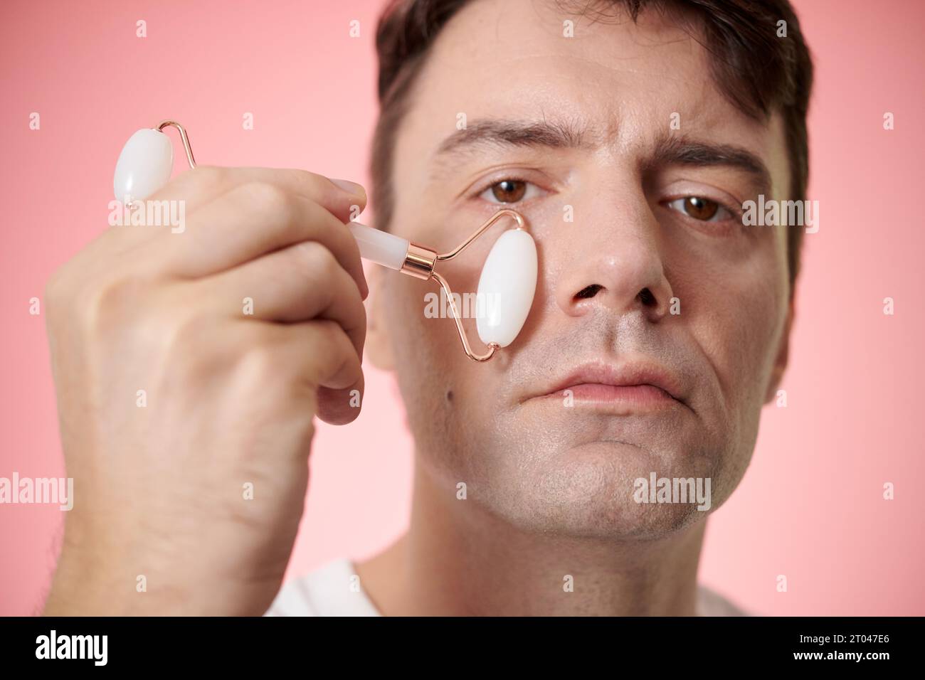 Portrait of mature man massaging cheeks with quartz roller Stock Photo ...