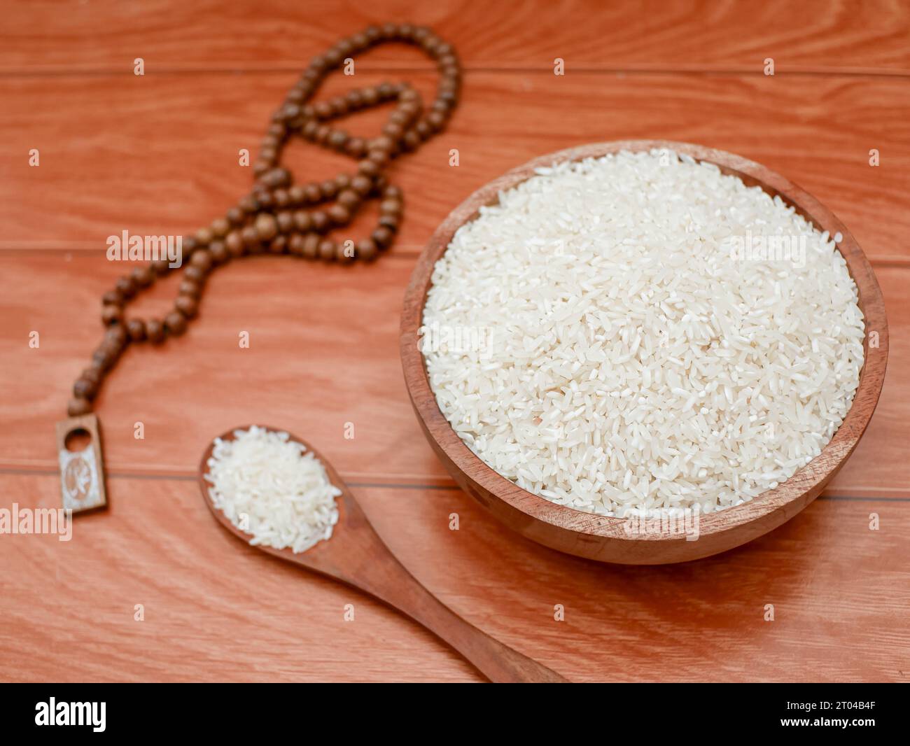 tasbeh and a grain of rice in a wooden bowl. Islamic zakat concept. Muslims to help the poor and needy Stock Photo