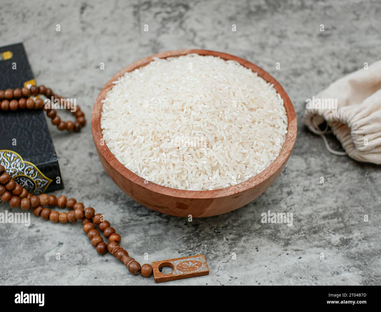 holy Quran and a grain of rice in a wooden bowl. Islamic zakat concept Stock Photo