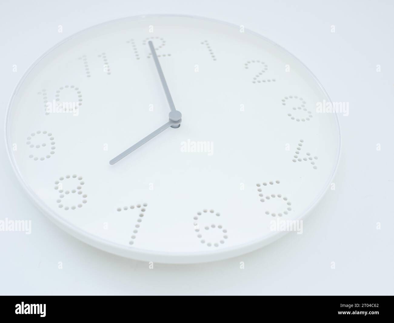 white wall clock shows the time 8 am or pm on white background Stock
