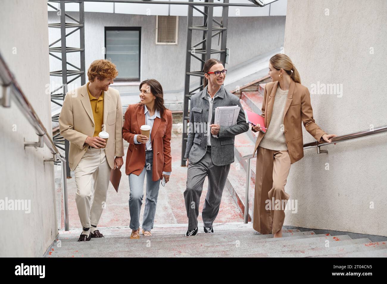 happy young team members walking upstairs talking and smiling at each other, coworking concept Stock Photo