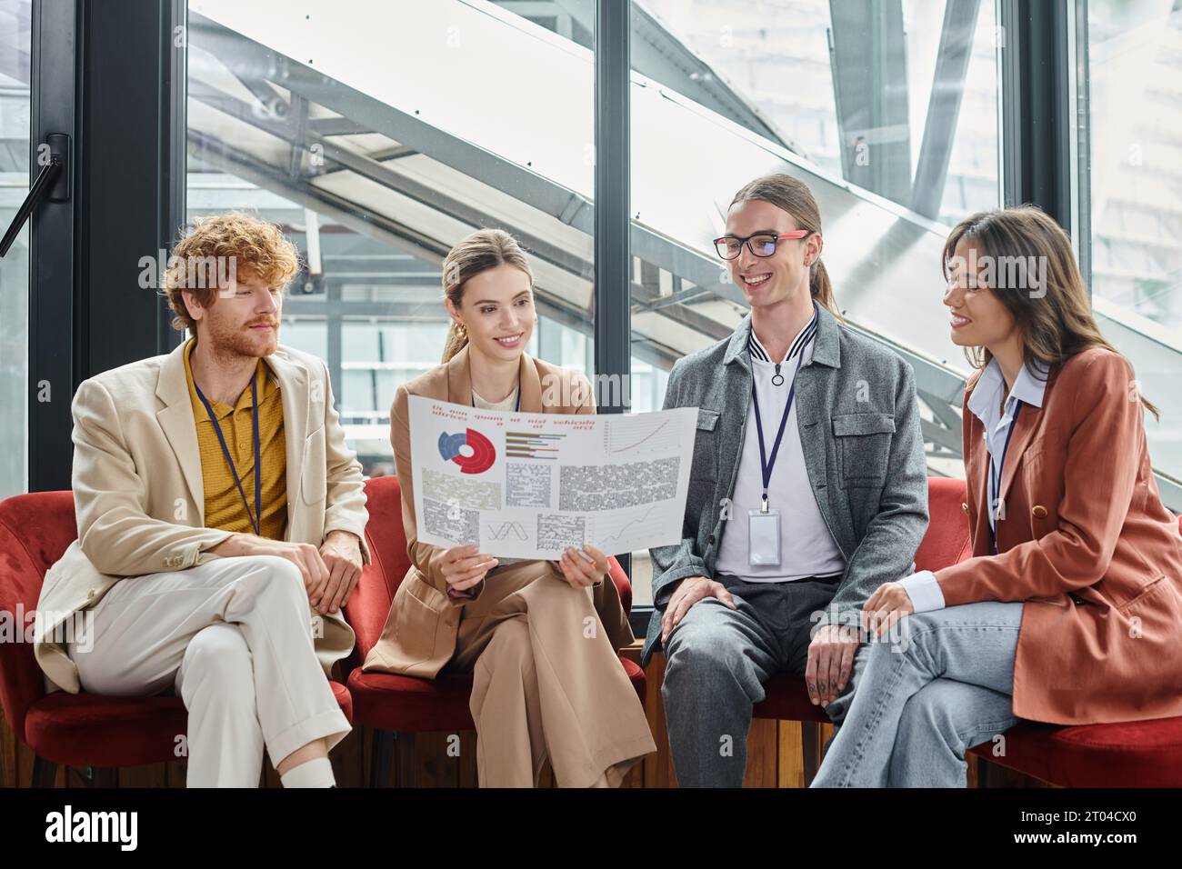 creative team looking at their paperwork with chart while sitting on chairs, coworking concept Stock Photo