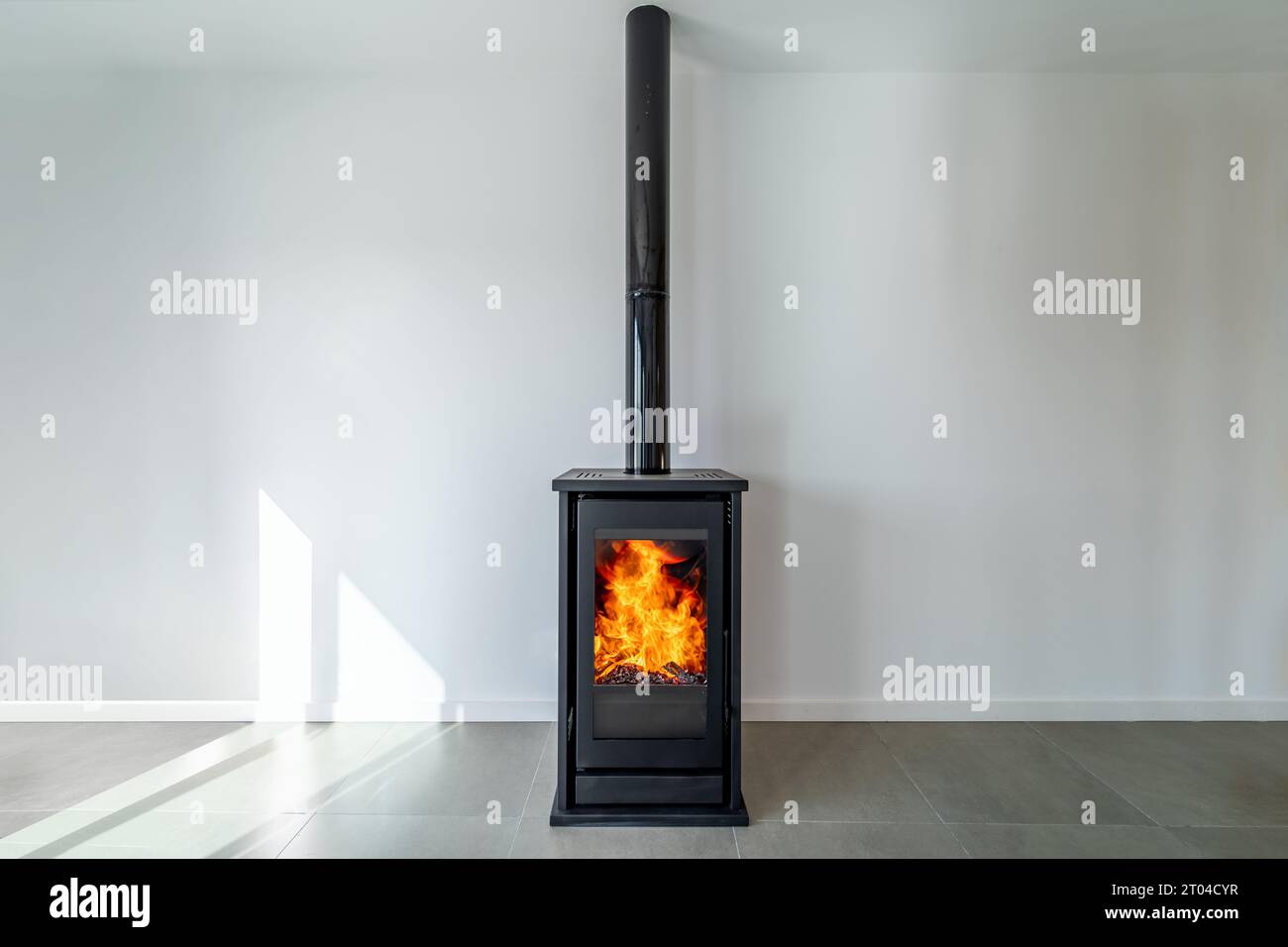 Fireplace inside house modern living room. Cosy living room with wood burner stove with burning flame behind a glass door Stock Photo