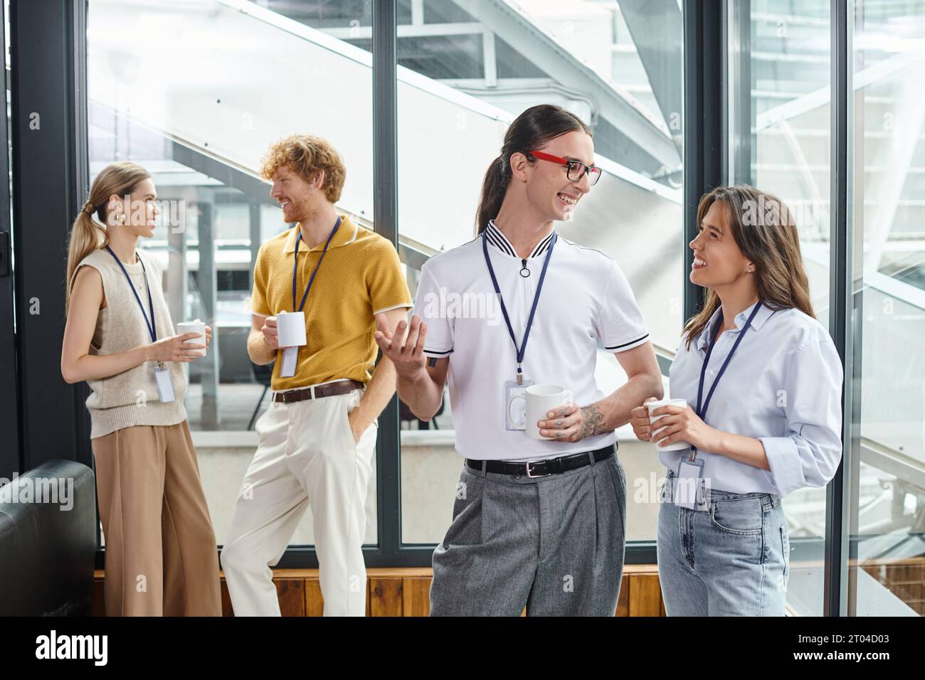 four cheerful coworkers in smart wear smiling each other at coffee break, coworking concept Stock Photo