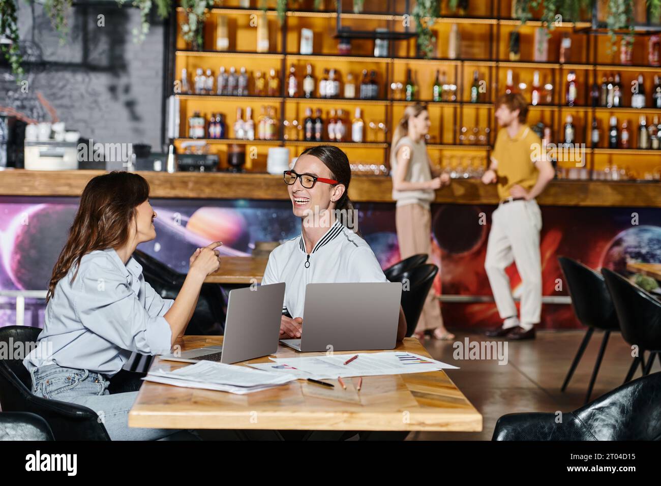 young team members chatting using laptops while their colleagues talking on background, coworking Stock Photo