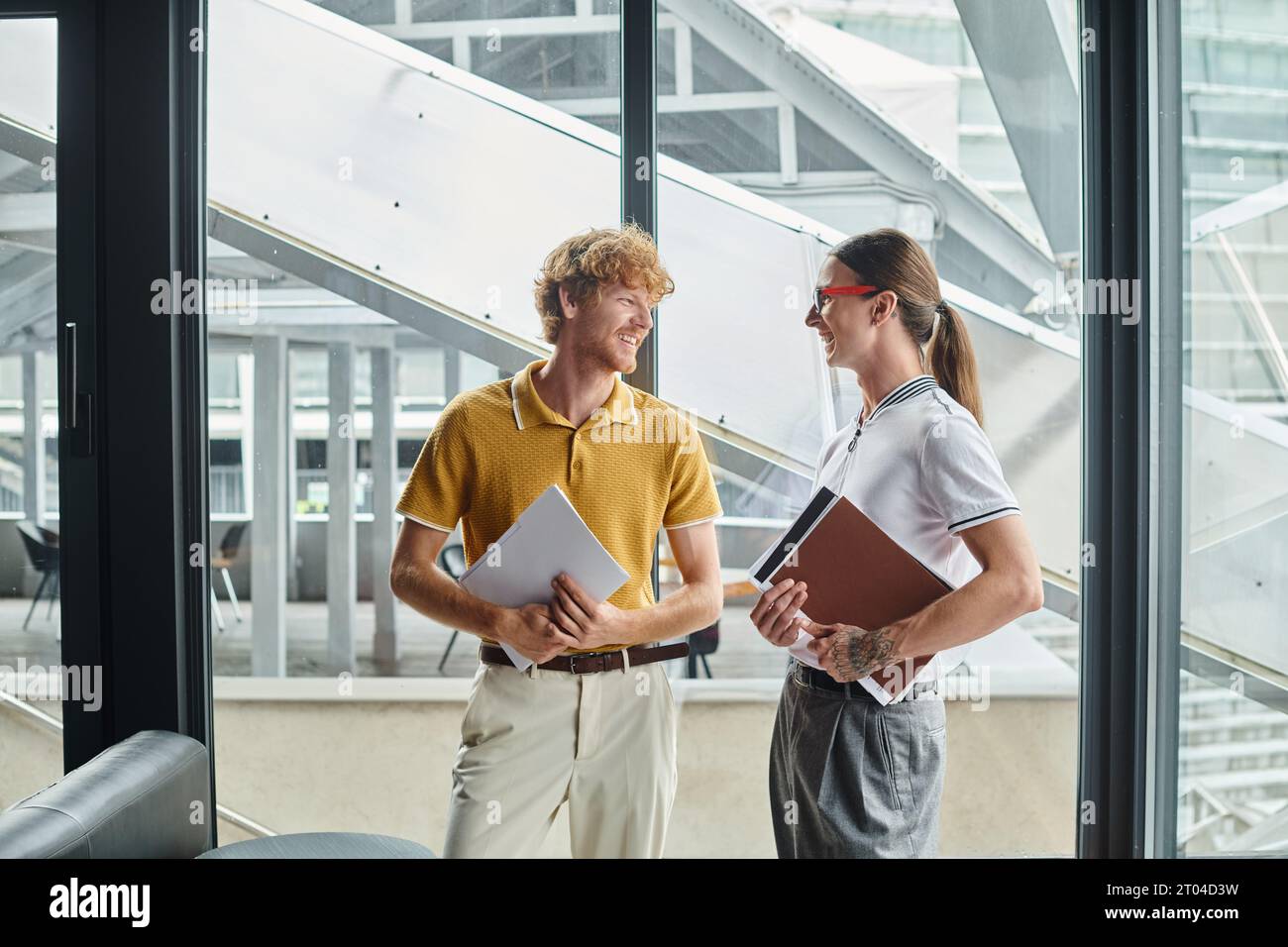 two male colleagues in business casual attire chatting and looking at each other, coworking concept Stock Photo