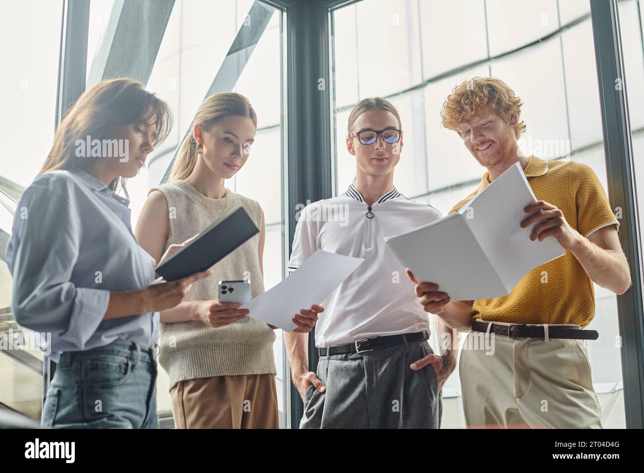 four coworkers in smart wear smiling, holding working papers and phone, close up, coworking concept Stock Photo