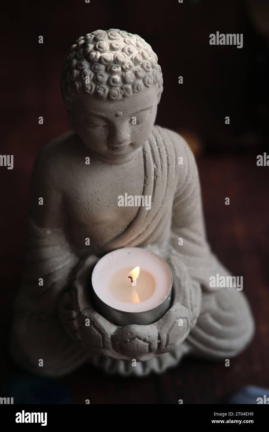 stone statue of buddha with a candle Stock Photo