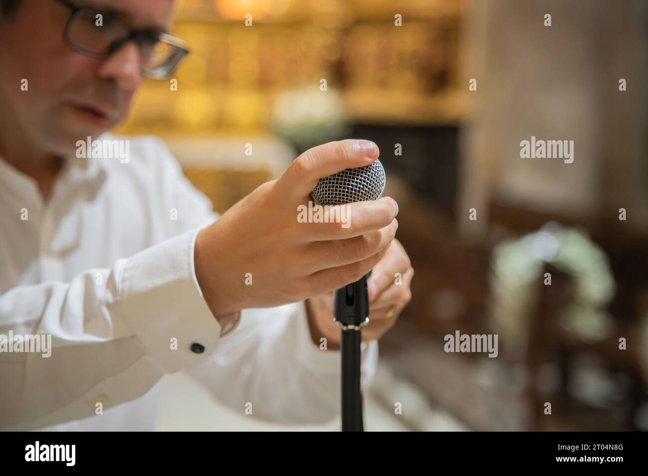 Man holding and preparing microphone to use in musical performance. Rustic interior environment, example temple or church. Close up Stock Photo