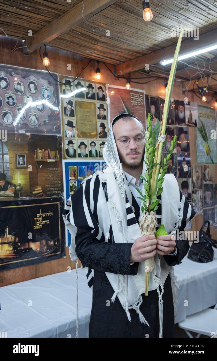 An orthodox Jewish man poses for a photo holding the 4 Sukkos species