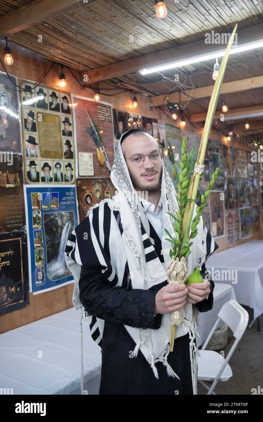 An orthodox Jewish man poses for a photo holding the 4 Sukkos species