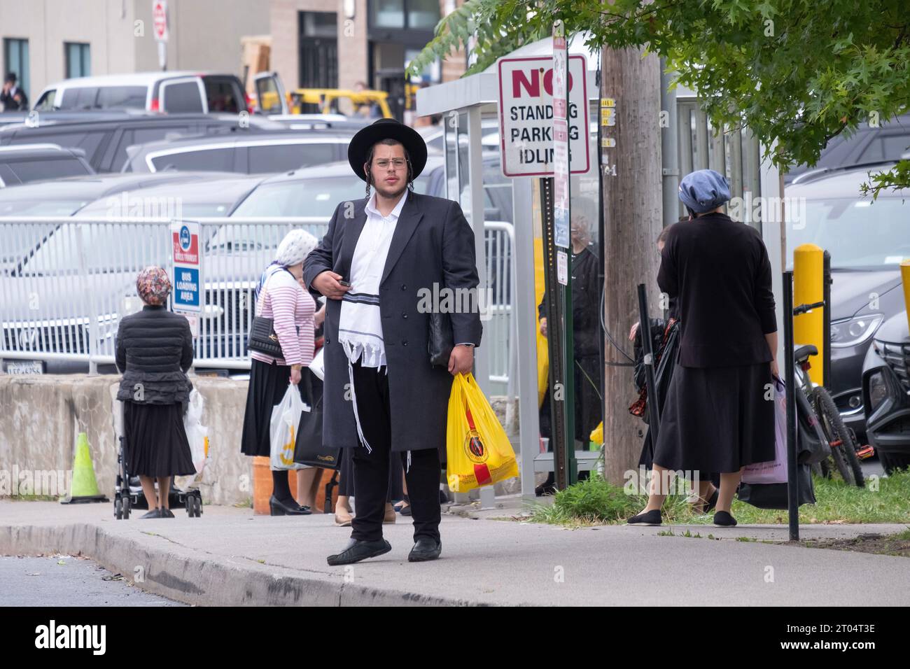 A hasidic Jewish man waits for a bus outside the Kiryas Joel Shopping Center on Forest Avenue. Respectfully, he stands apart from the women. Stock Photo