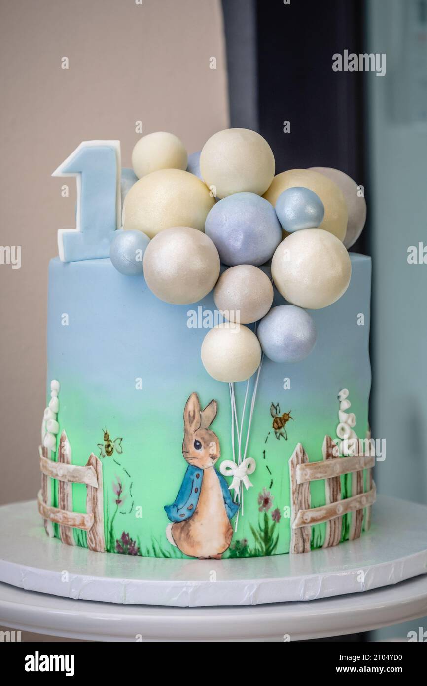 A delightful cake adorned with colorful balloons and an adorable rabbit, celebrating a baby's joyful first birthday Stock Photo