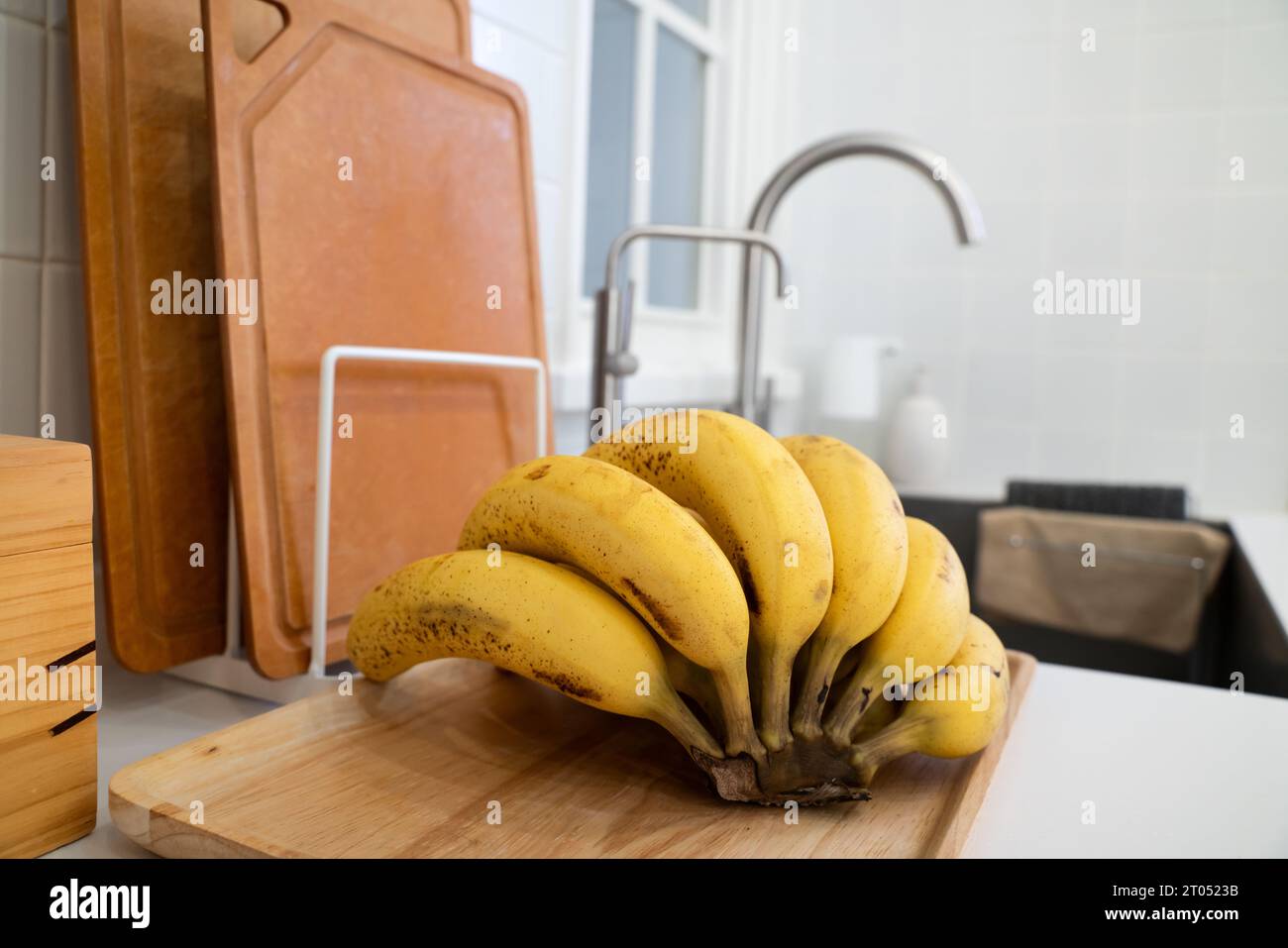 A bunch of fresh banana lie on the table in a modern kitchen, healthy life concept. Stock Photo