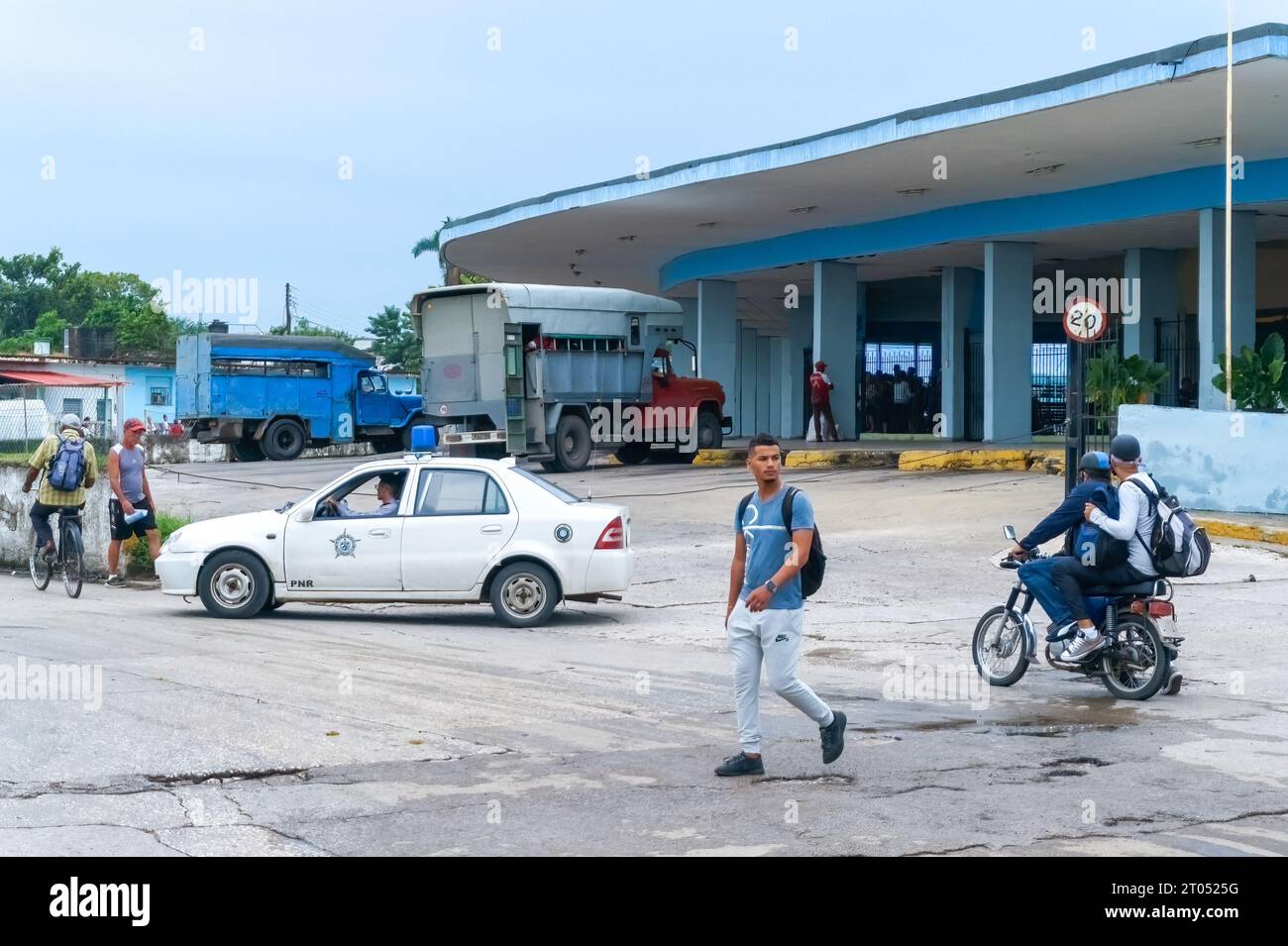 A PNR or Revolutionary National Police car drives by the Intermunicipal Bus Terminal. The patrol vehicle moves by a couple in a motorcycle and other i Stock Photo