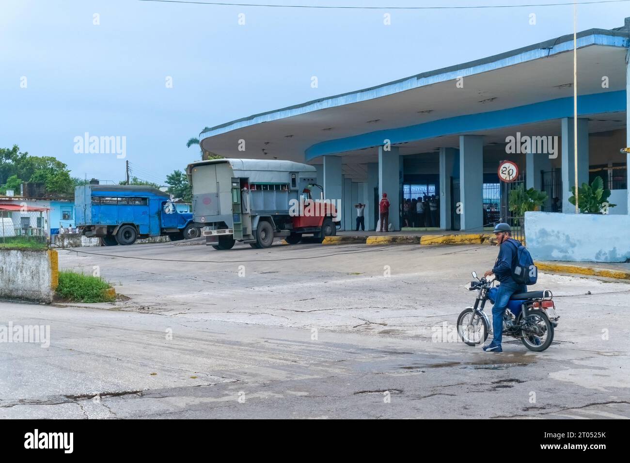 A man rides a motorcycle by the Intermunicipal BusTerminal. Instead of buses, transportation is accomplished by privately operated trucks arrange to m Stock Photo