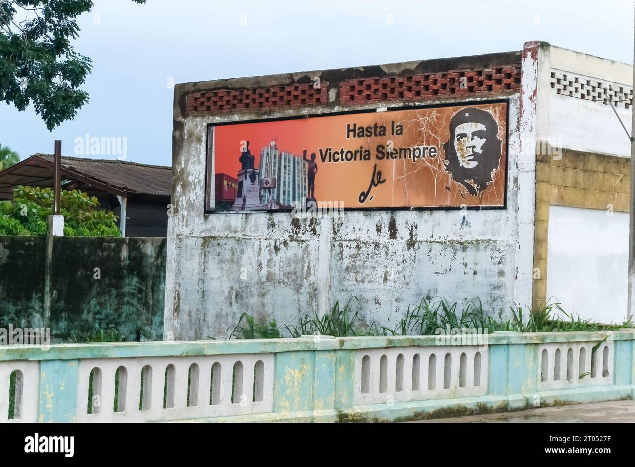 A billboard of Che Guevara in a weathered old building. There is a text in Spanish language reading: Hasta La Victoria Siempre.Santa Clara, Cuba, 2023 Stock Photo