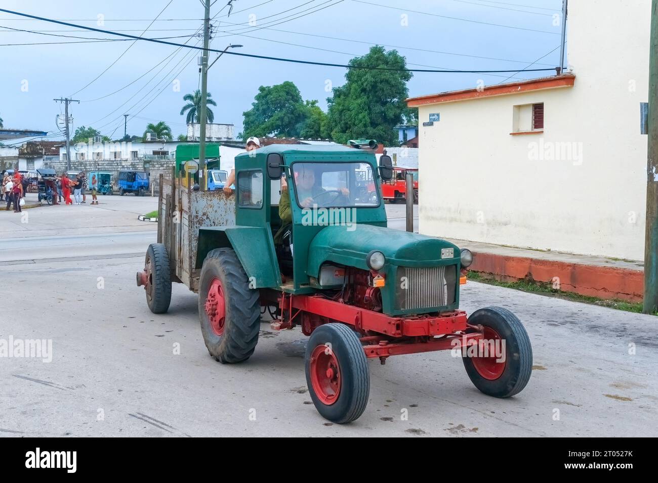 A man with a military shirt drives an old agricultural tractor on a city street.Santa Clara, Cuba, 2023 Stock Photo
