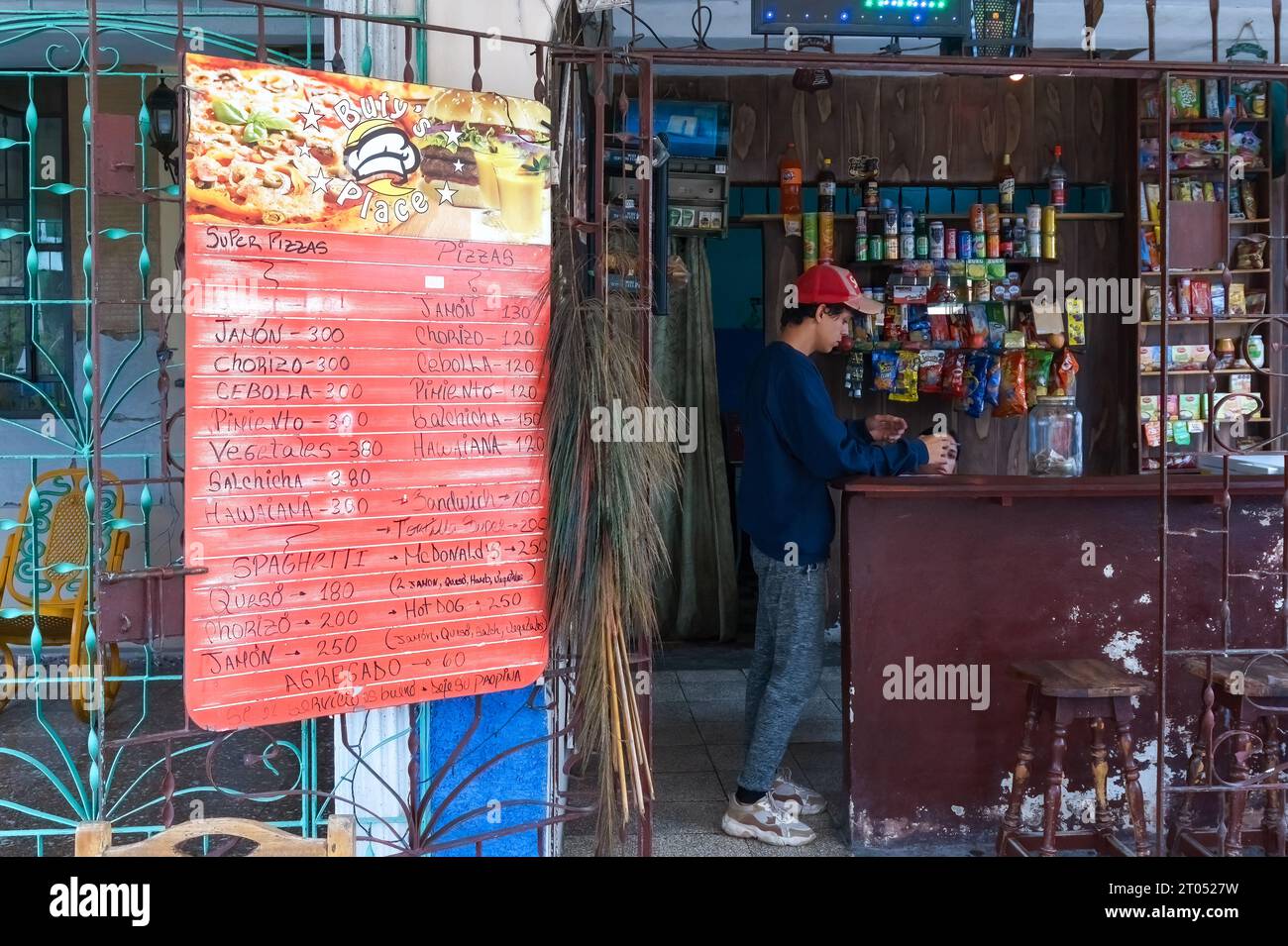 A young Cuban man working in a small private business. The high prices caused by inflation appear in a board in the exteriorSanta Clara, Cuba, 2023 Stock Photo