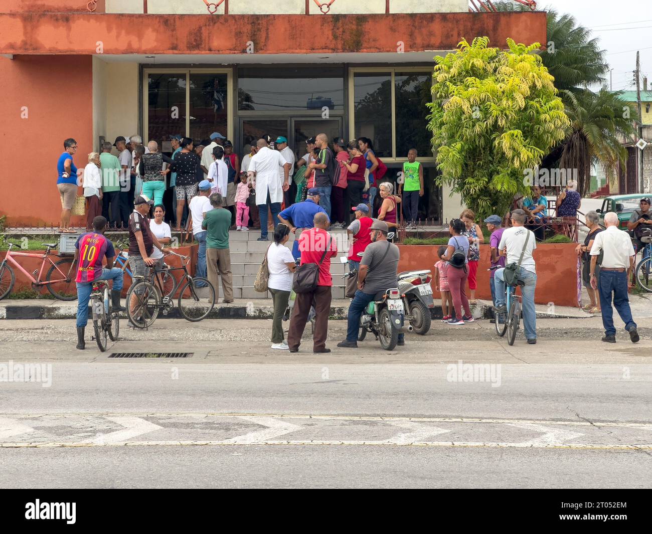 Crowd of people in the exterior of a bank branch. Some are waiting for services, others line-up to get money from the ATM machine.Santa Clara, Cuba, 2 Stock Photo