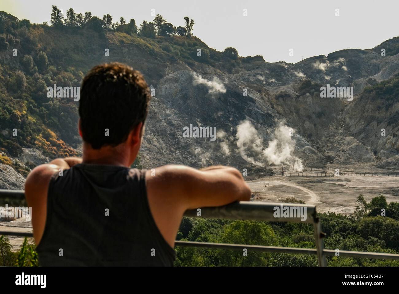 A tourist looks curiously at the crater of the solfatara, it is one of the forty volcanoes that make up the Phlegraean Fields; it is located about three kilometres from the centre of the city of Pozzuoli, it is the epicentre of the seismic swarm that has occurred in recent days, the strongest tremor the day before yesterday of magnitude 4.2 recorded by the Monitoring Network of the Vesuvius Observatory of the National Institute of Geophysics and Volcanology (INGVA generic view of the solfatara, it is one of the forty volcanoes that make up the Phlegraean Fields; it is located about three kilom Stock Photo
