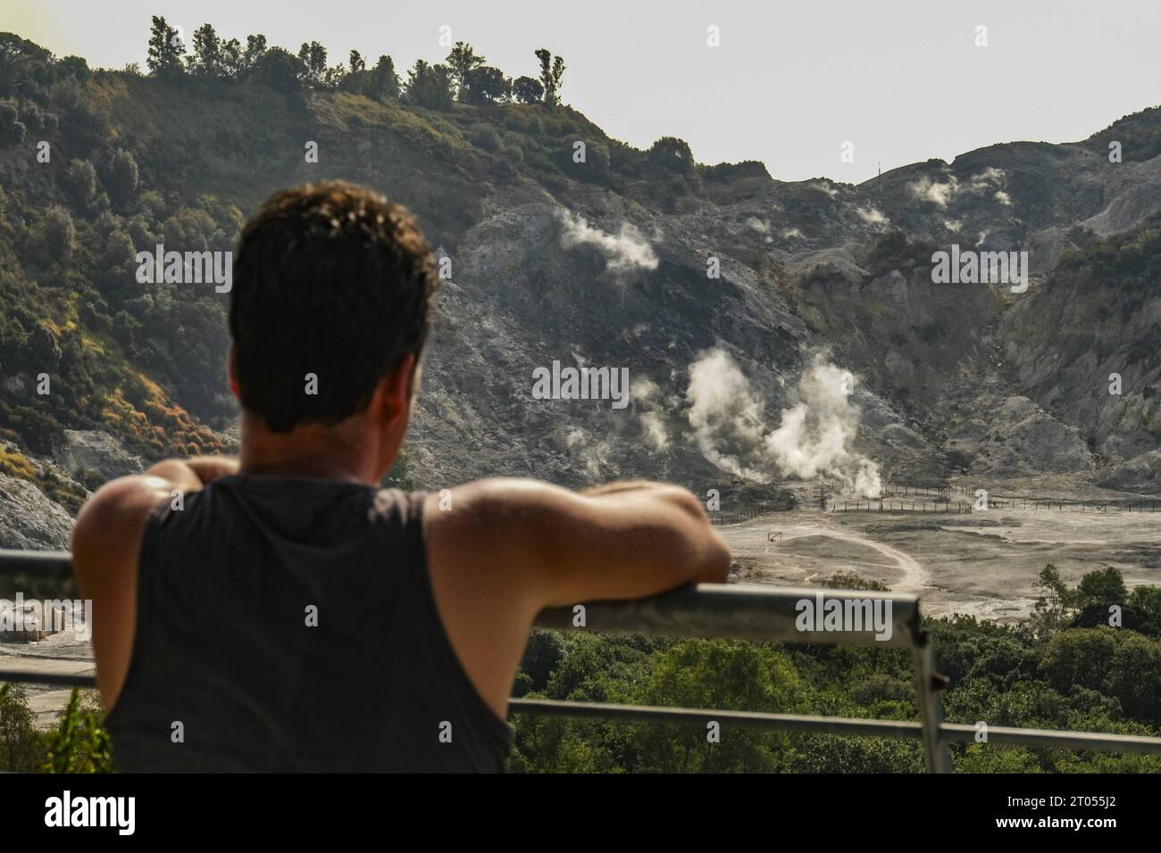 Reportage - Campi Flegrei A tourist looks curiously at the crater of the solfatara, it is one of the forty volcanoes that make up the Phlegraean Fields it is located about three kilometres from the centre of the city of Pozzuoli, it is the epicentre of the seismic swarm that has occurred in recent days, the strongest tremor the day before yesterday of magnitude 4.2 recorded by the Monitoring Network of the Vesuvius Observatory of the National Institute of Geophysics and Volcanology INGVA generic view of the solfatara, it is one of the forty volcanoes that make up the Phlegraean Fields it is lo Stock Photo