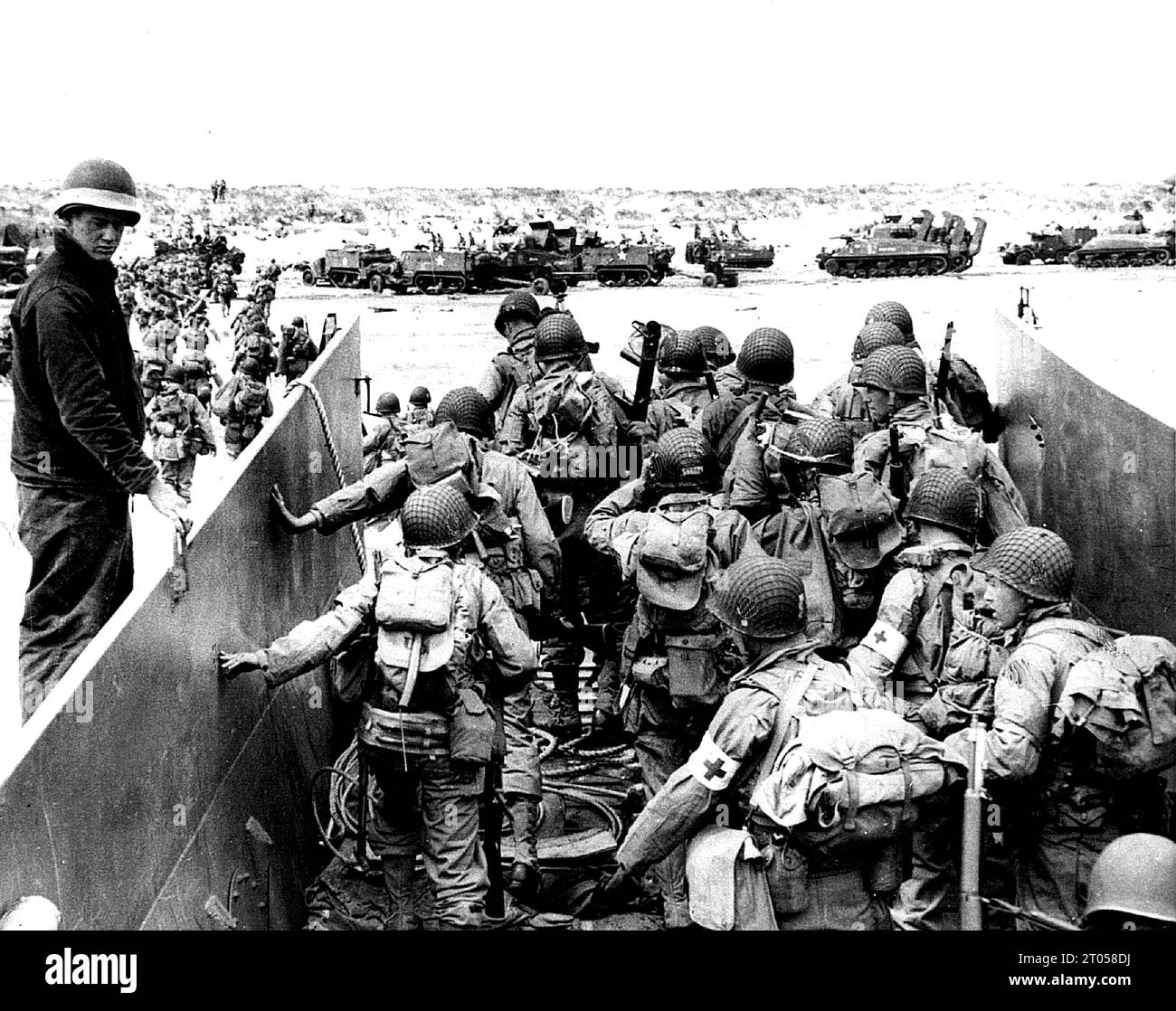PA PHOTOS/DPA - UK USE ONLY: US Army soldiers disembark from a landing craft during the Normandy landings (D-Day) of 6th June 1944. Sherman tanks and White half-tracks can be seen drawn up on the beach. Stock Photo