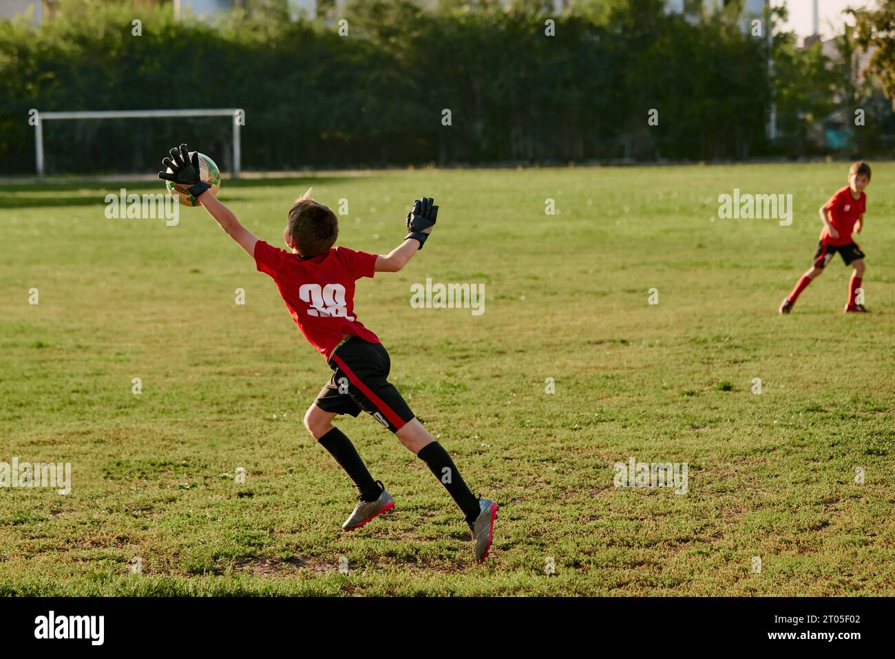 Rear view portrait of goalkeeper, kid beats arm flying ball from