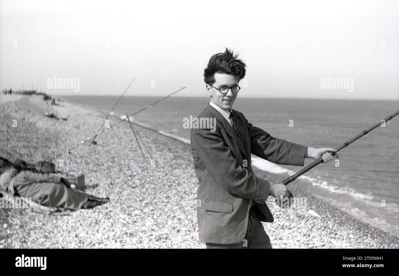 https://c8.alamy.com/comp/2T05MH1/1950s-historical-a-young-man-early-twenties-wearing-a-sports-jacket-shirt-tie-outside-on-a-sloping-beach-standing-holding-a-fishing-rod-doing-some-sea-fishing-england-uk-2T05MH1.jpg