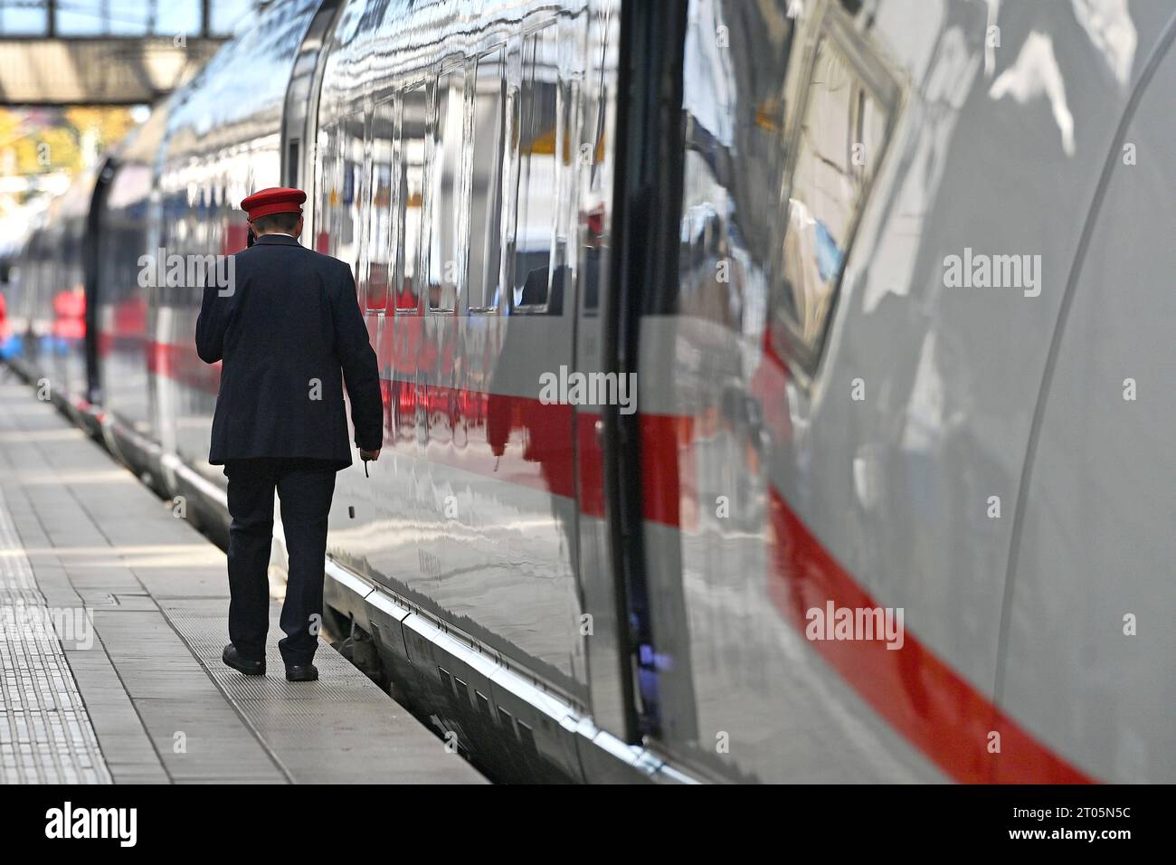 Zugfuehrer, Schaffner, Zugbegleiter geht an einem ICE entlang.Intercity