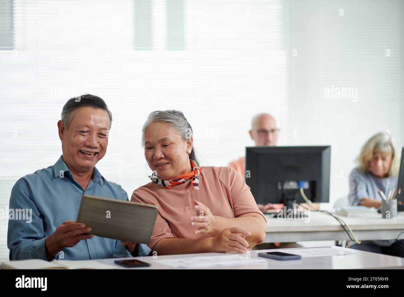 Serious couple attending computer class to learn how to use application on digital tablets Stock Photo
