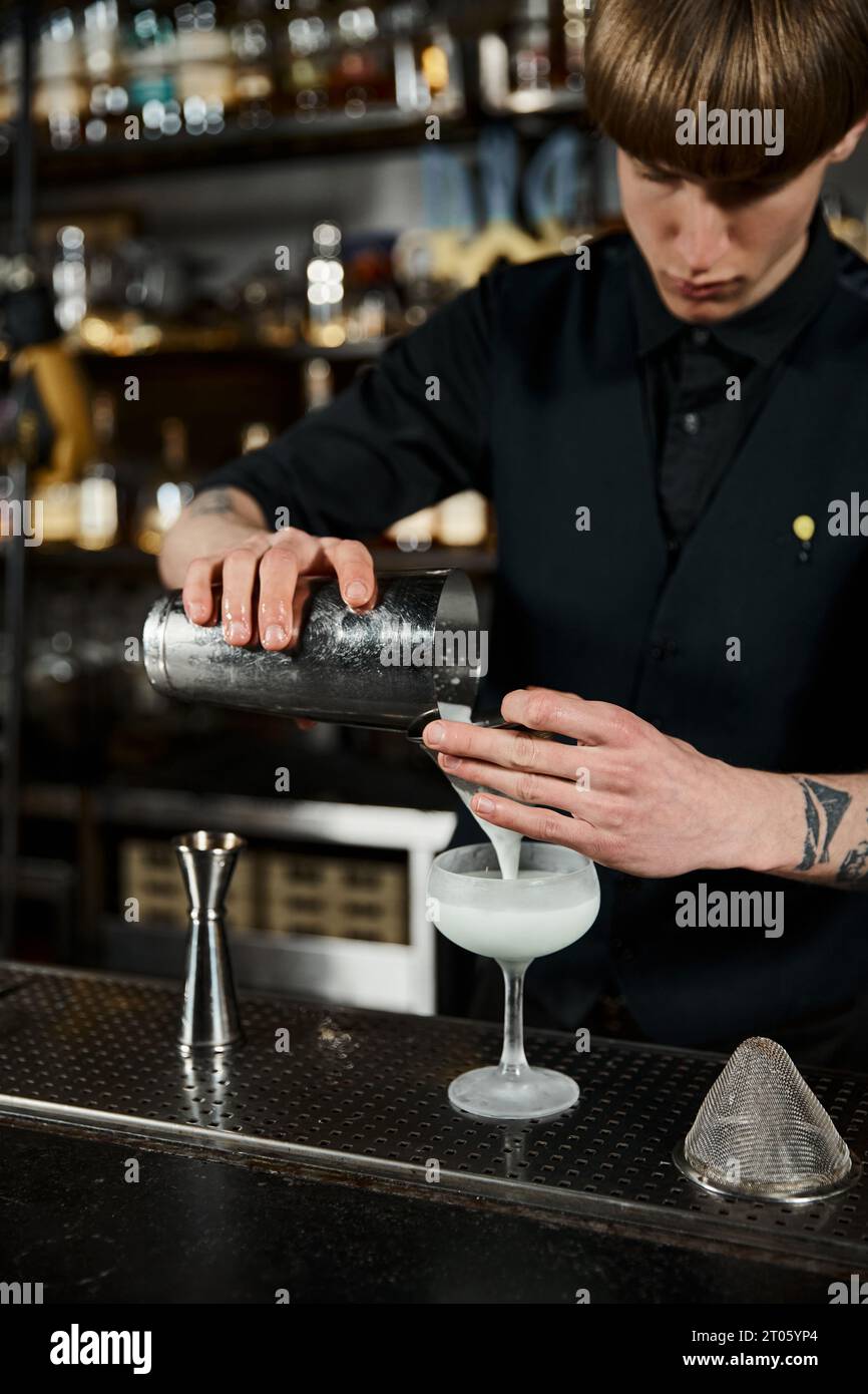 cropped view of bartender with cocktail shaker preparing milk punch on bar counter, drink mixology Stock Photo