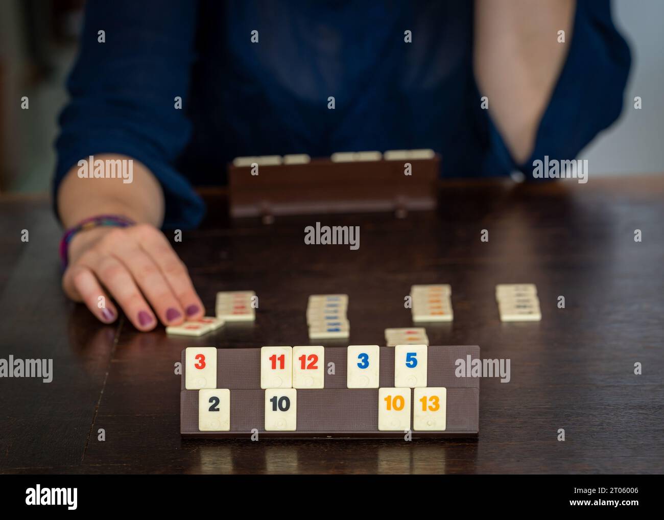 Two players playing a popular board game, rummikub tiles on the wooden table Stock Photo