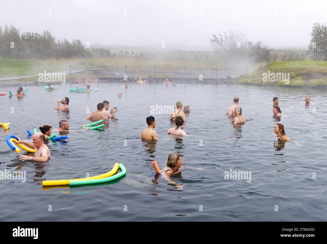 Iceland hot springs - people bathing in the Secret Lagoon, a geothermal spa pool with natural hot water, from thermal energy, Reykjavik, Iceland. Stock Photo