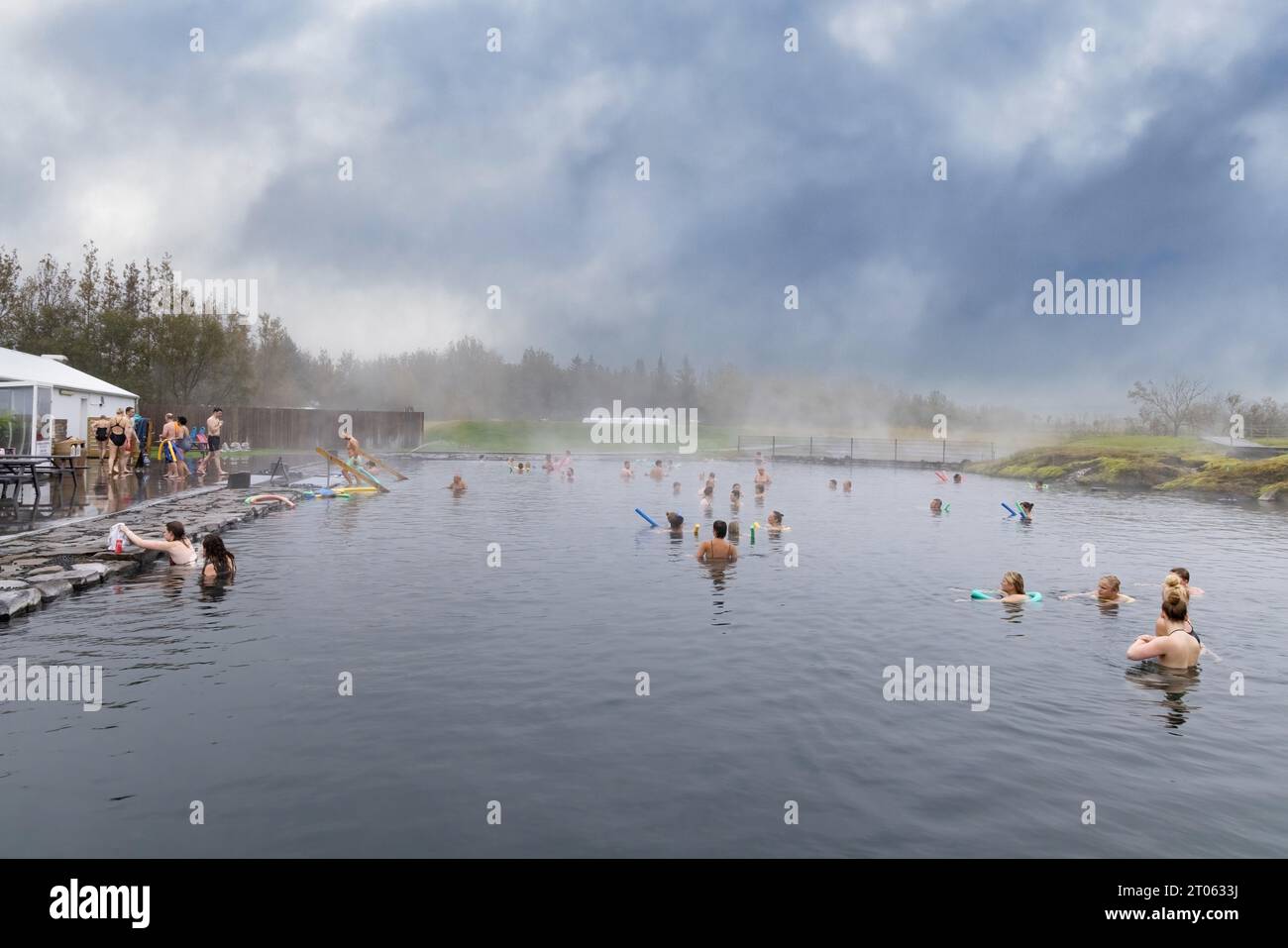 Iceland hot springs - people bathing in the Secret Lagoon, a geothermal spa pool with natural hot water, from thermal energy, Reykjavik, Iceland. Stock Photo