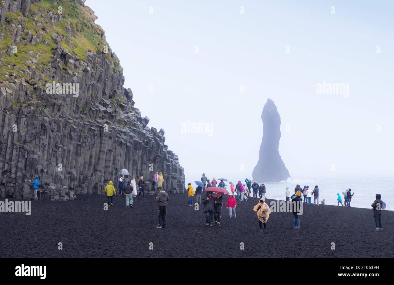 Iceland coast; people on Vik black sand beach, or Reynisfjara beach, Iceland South Coast, basalt cliffs and results of volcanic activity; Vik, Iceland Stock Photo