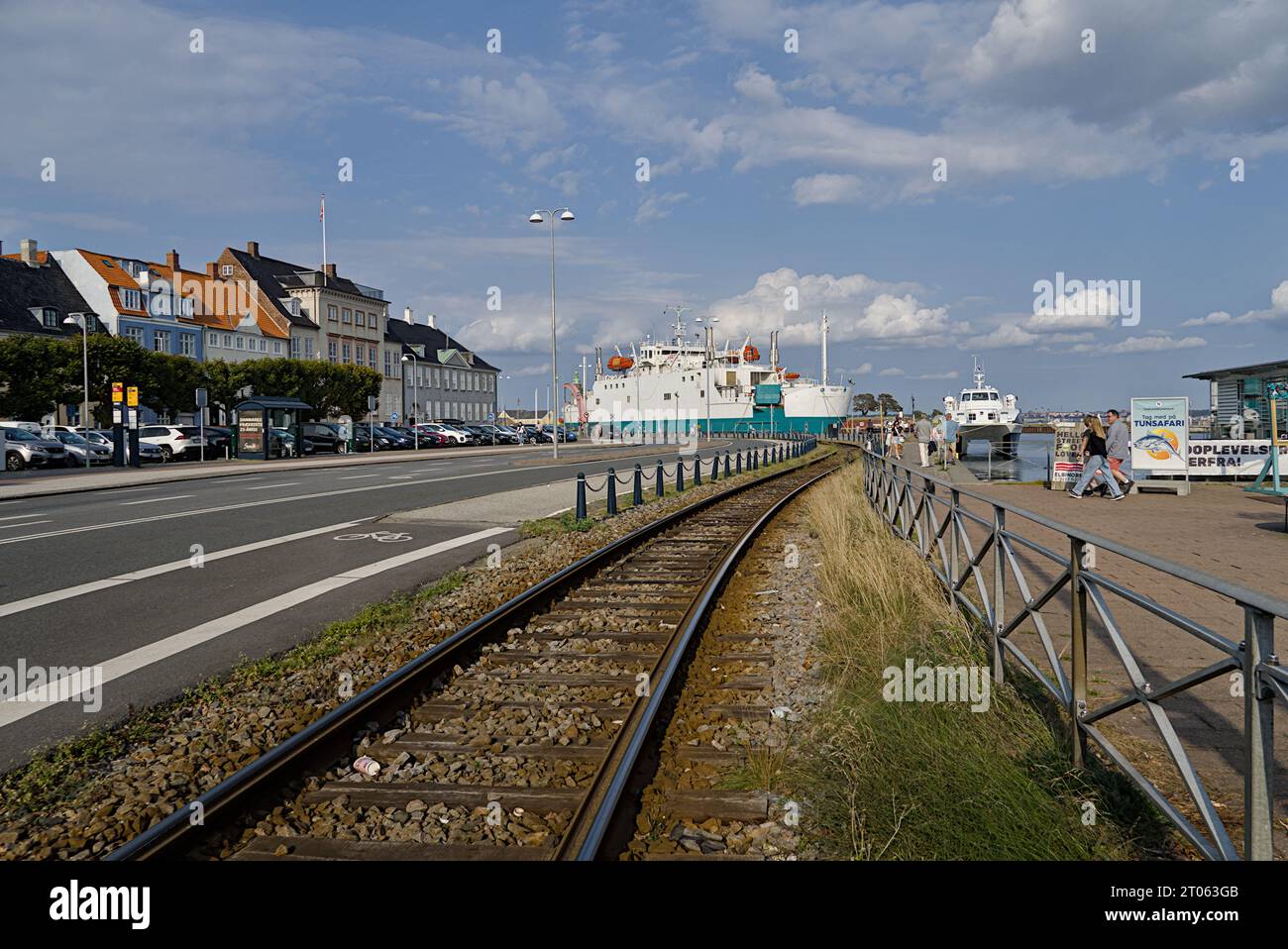 Paved road and train tracks leads to the ship docked at the harbor. Stock Photo