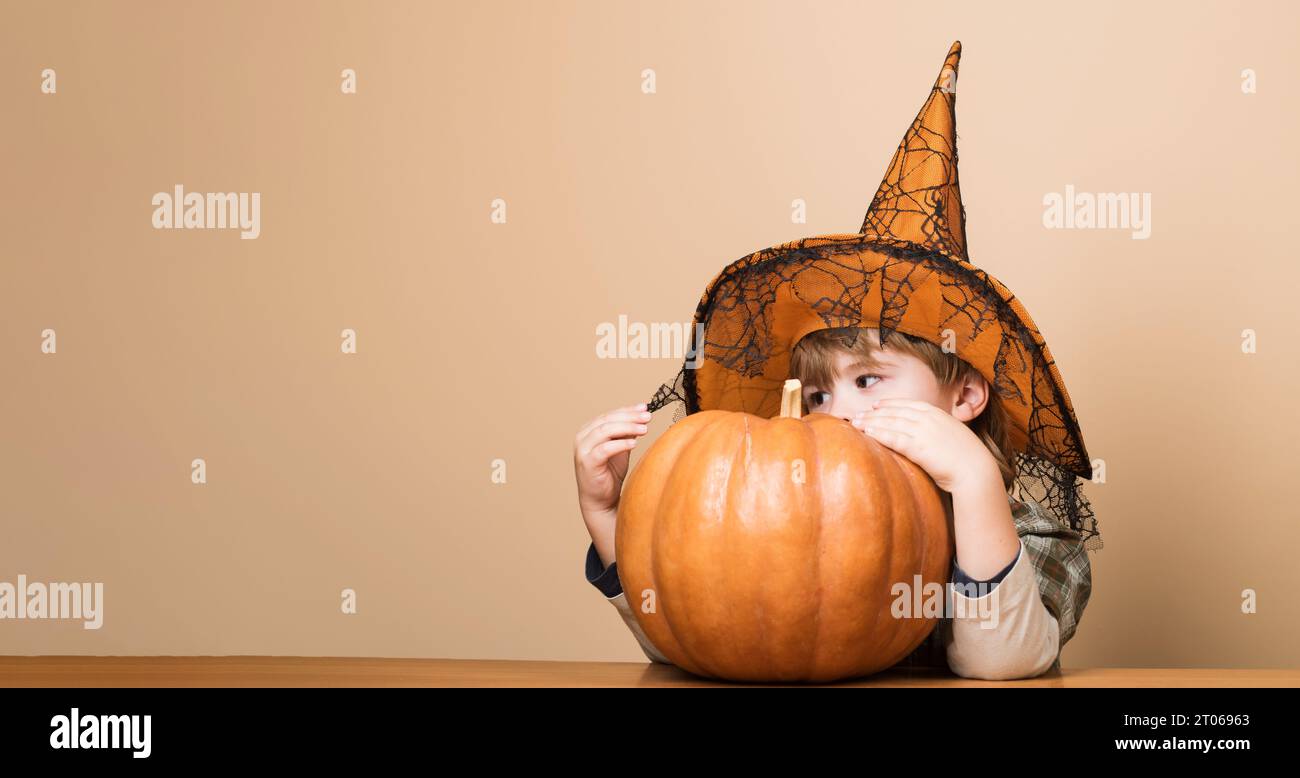 Happy Halloween. Little kid wizard, magician prepares for Halloween holiday. Halloween boy in witch hat with pumpkin. Cute child with jack-o-lantern Stock Photo