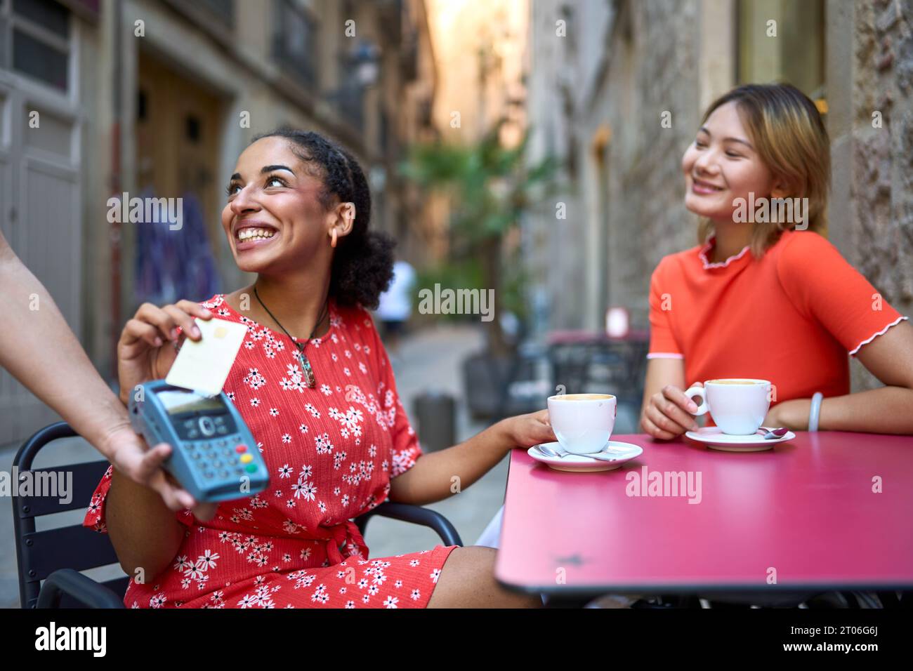 Friends paying with credit card sitting in a cafeteria Stock Photo