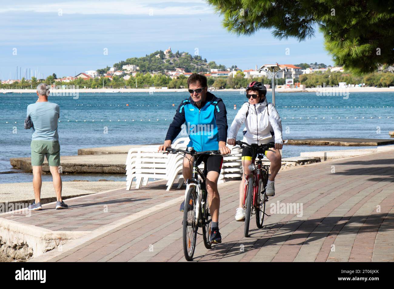 Vodice, Croatia - September 24, 2023: Mature couple riding bikes at the promenade by the seaside beach Stock Photo