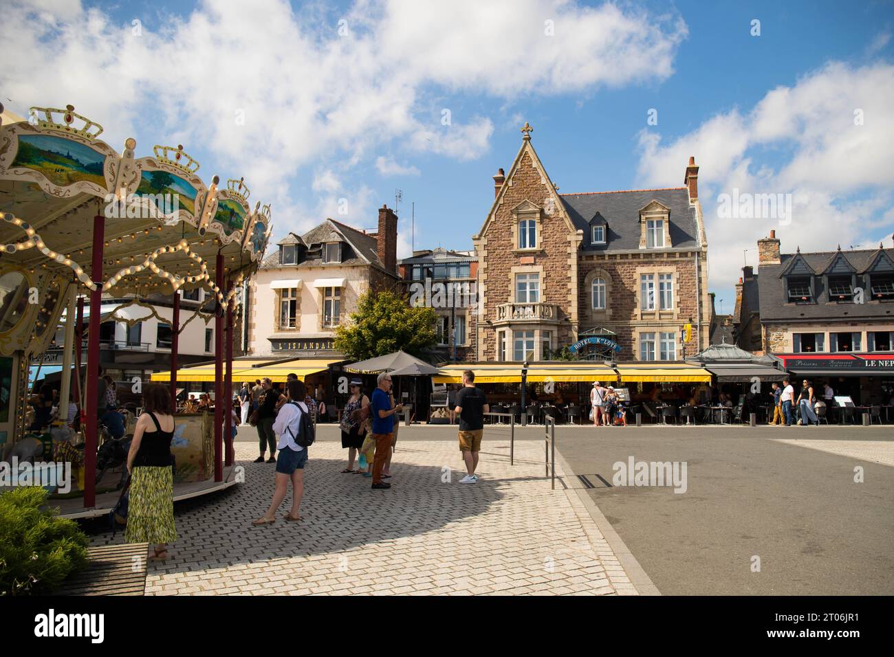 PAIMPOL, FRANCE, AUGUST 2023 - The old carousel and typical buildings with tourists in the center of Paimpol, a charming town in  Brittany. Stock Photo