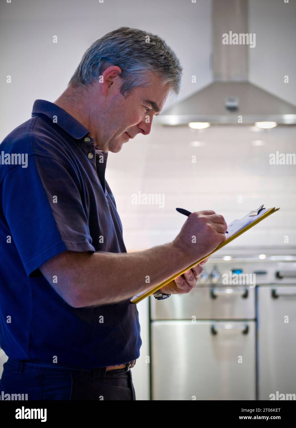 Man clipboard carbon emissions survey property related sales design maintenance refurbishment quotation person, in contemporary domestic kitchen UK Stock Photo