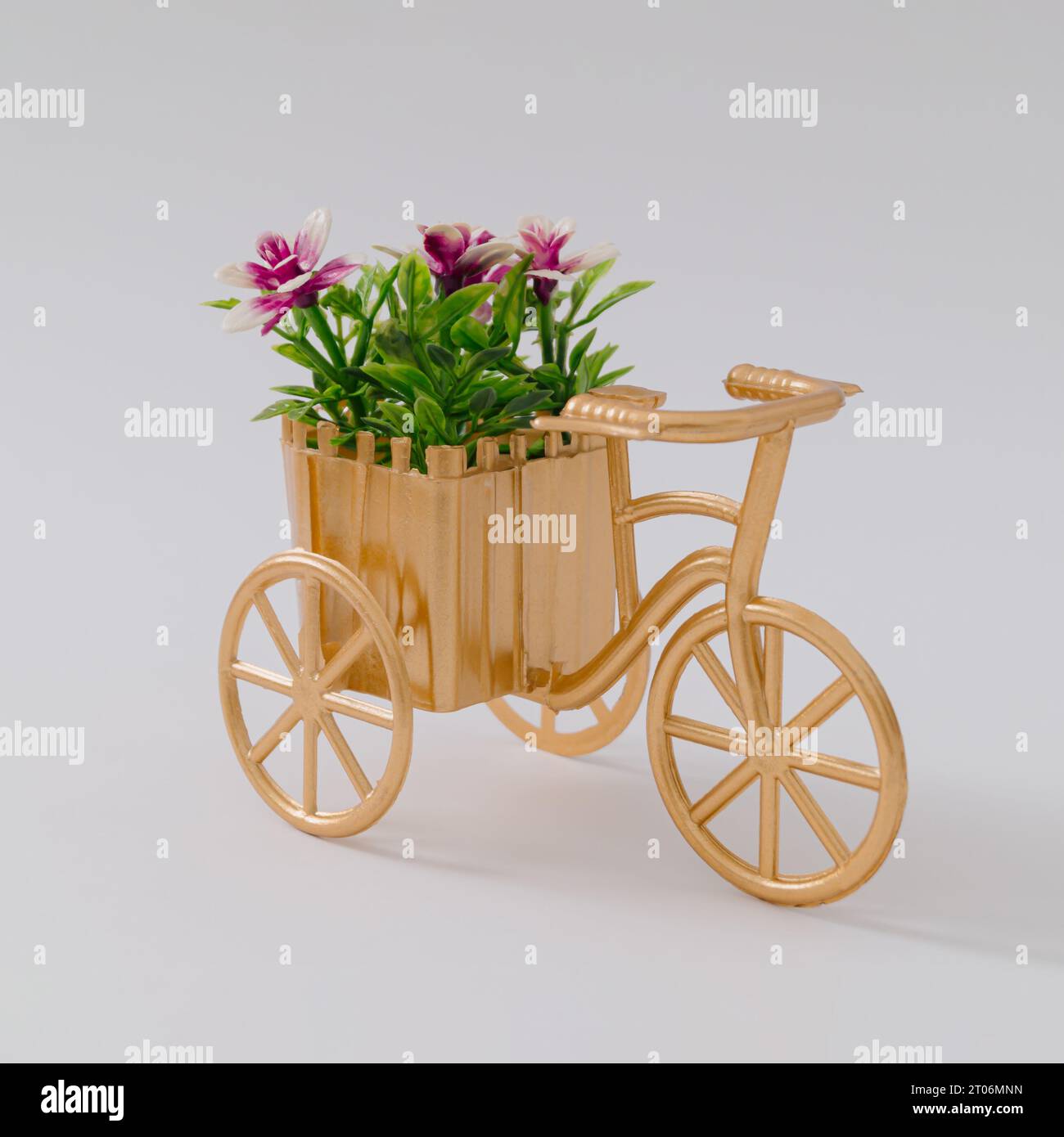 Retro golden bike with flowers against white background. Creative flower delivery concept. Minimal bike and flowers idea. Natural romantic card. Stock Photo