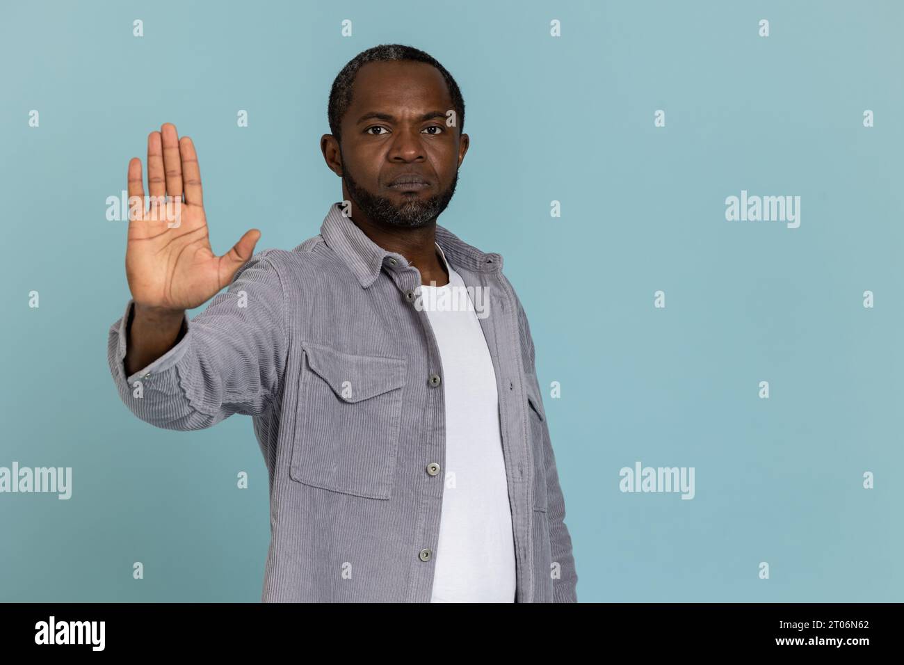 Serious black man wearing gray shirt showing stop sign Stock Photo