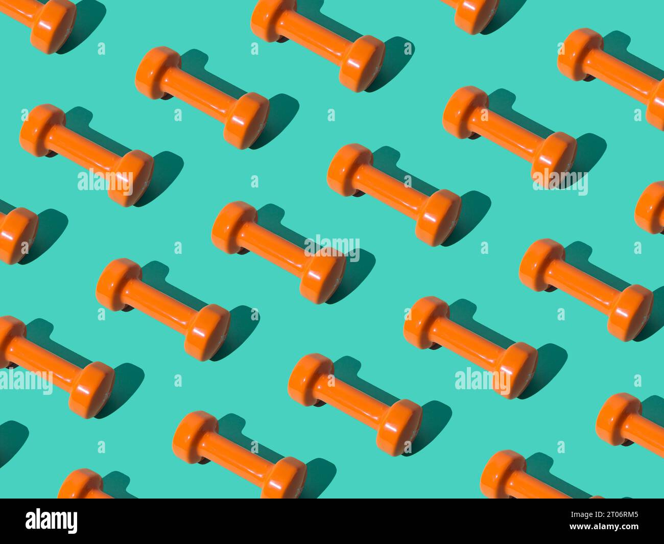 Creative pattern composition made of orange dumbbells on pastel green background. Minimal fitness, healthy lifestyle and sport concept. Stock Photo