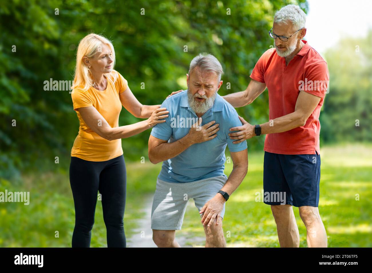 Senior man suffering from heart attack while training with friends in park Stock Photo