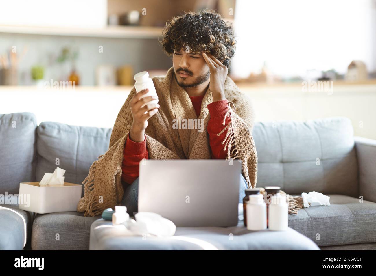 Sick Indian Man Holding Bottle With Pills While Sitting At Home Stock Photo