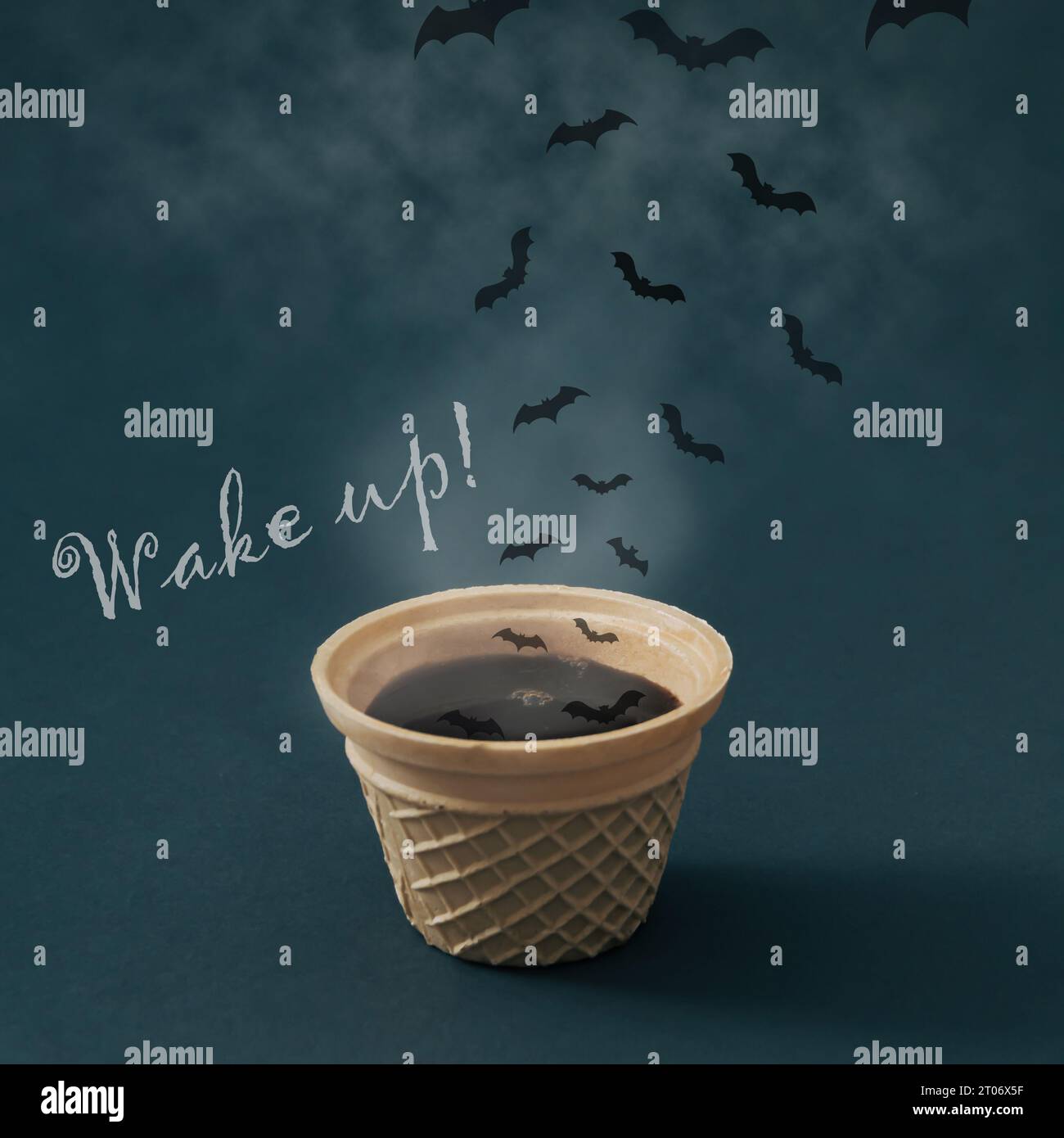 Hot steaming coffee in waffle ice cream cone, clouds and bats with 'Wake up!' message. Minimal coffee concept. Creative ice cream coffee idea. Stock Photo